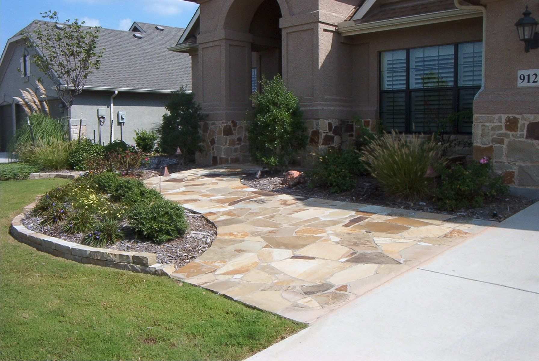 Flagstone walkway curving to a front entry, edged with stone borders and ornamental grasses
