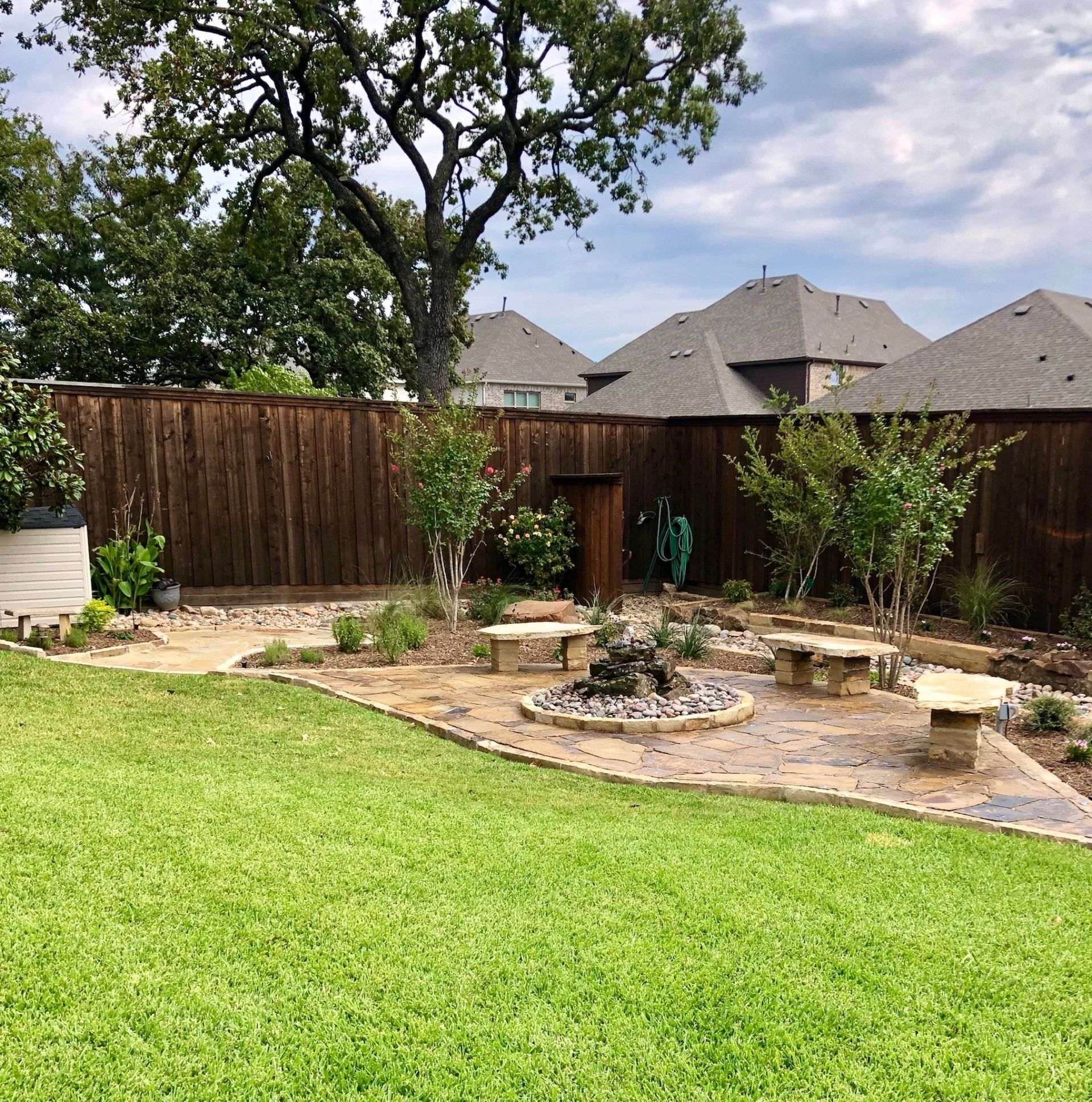 Finished backyard landscape with a stone-bordered bed and new plantings
