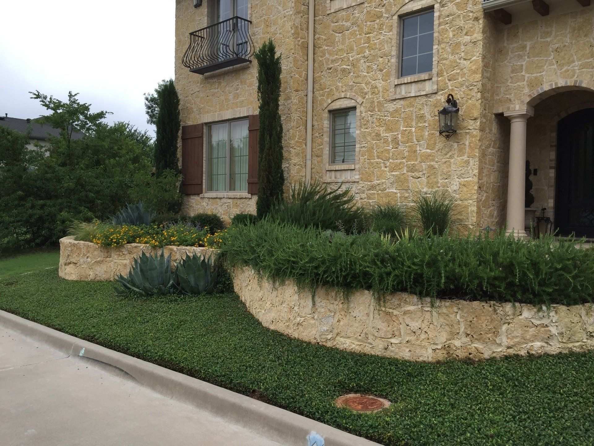 Stone-edged front lawn and foundation planting at a stone house